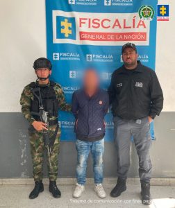 Un servidor del CTI Atlántico y un agente de la Policía Nacional custodian al procesado. 