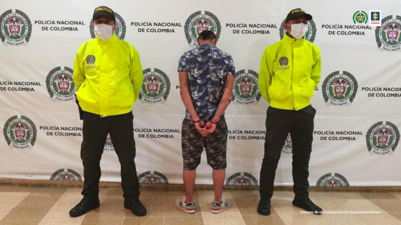 En la fotografía aparece un hombre capturado, de espaldas, con personal de la Policía Nacional, uno a cada lado. En la parte posterior de la imagen se ve un banner de la Policía Nacional.