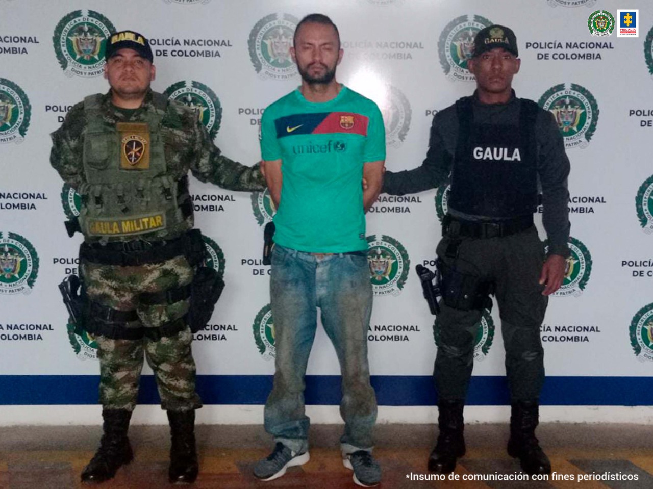 En la fotografía se observa al capturado de frente y en cada costado un funcionario de Policía Gaula. Atrás el pendón de Policía Nacional
