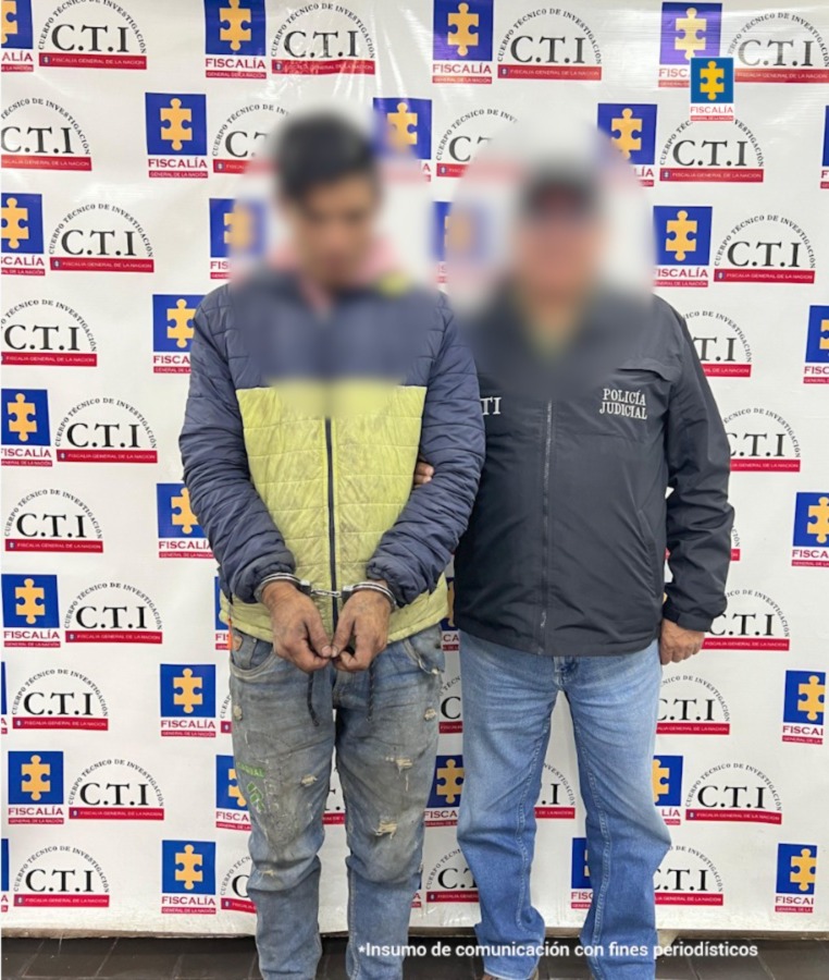 fotografia del capturado custodiado por un funcionario del CTI, detras de ellos hay un baking de la fiscalia