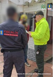en vía pública capturado de frente, policía leyéndole orden de captura y derechos, de espalda investigador del CTI de la fiscalía