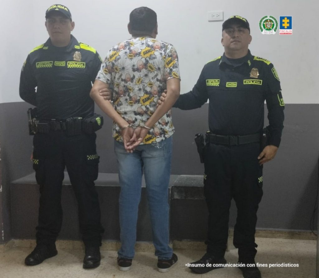 capturado de espaldas custodiado por dos policías.