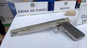 En una mesa aparecen los elementos incautados como armas, celulares estupefacientes y de fondo, están los capturados esposados y custodiados por uniformados de la Policía Nacional.