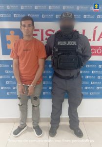 En la imagen se ve a un hombre, identificado como Carlos Andrés Quintero Ovalle, alias Chango, quien sería el presunto responsable de ocasionarle la muerte a una niña de 12 años, junto a un uniformado de policía judicial. 