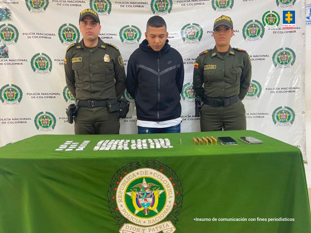 Un hombre, identificado como Cristian Darío Dorado Hernández, aparece esposado, con las manos hacia atrás, en compañía de dos uniformados de la Policía Nacional. Los tres están de pie, y detrás de ellos se observa un fondo institucional de la Policía.