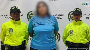 La investigada quien fue capturada durante unas visitas que realizaba la Policía Nacional y el ICBF en un establecimiento comercial es custodiada por dos uniformados. 