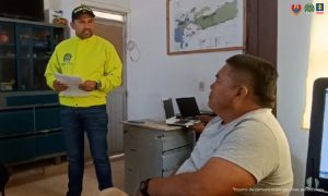 En una mesa aparecen los elementos incautados como armas, celulares estupefacientes y de fondo, están los capturados esposados y custodiados por uniformados de la Policía Nacional.