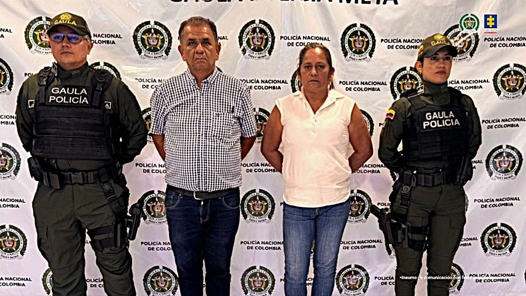 capturados de frente, custodiados por policías. Detrás banner de la Policía Nacional.