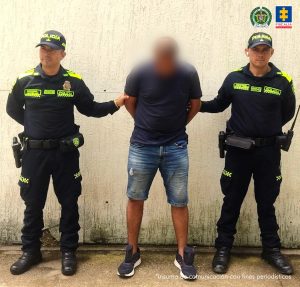 Los hombres aparecen con sus manos esposadas y custodiados por uniformados de la policía nacional. 