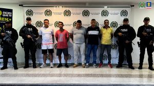 Los imputados se encuentran en custodia por dos uniformados del Gaula de la Policía Nacional. Detrás de él se observa un backing de la Policía.