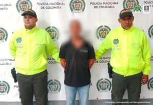 Dos uniformados de la Policía Nacional custodian al procesado tras su captura en el barrio El Rosario de Barranquilla.