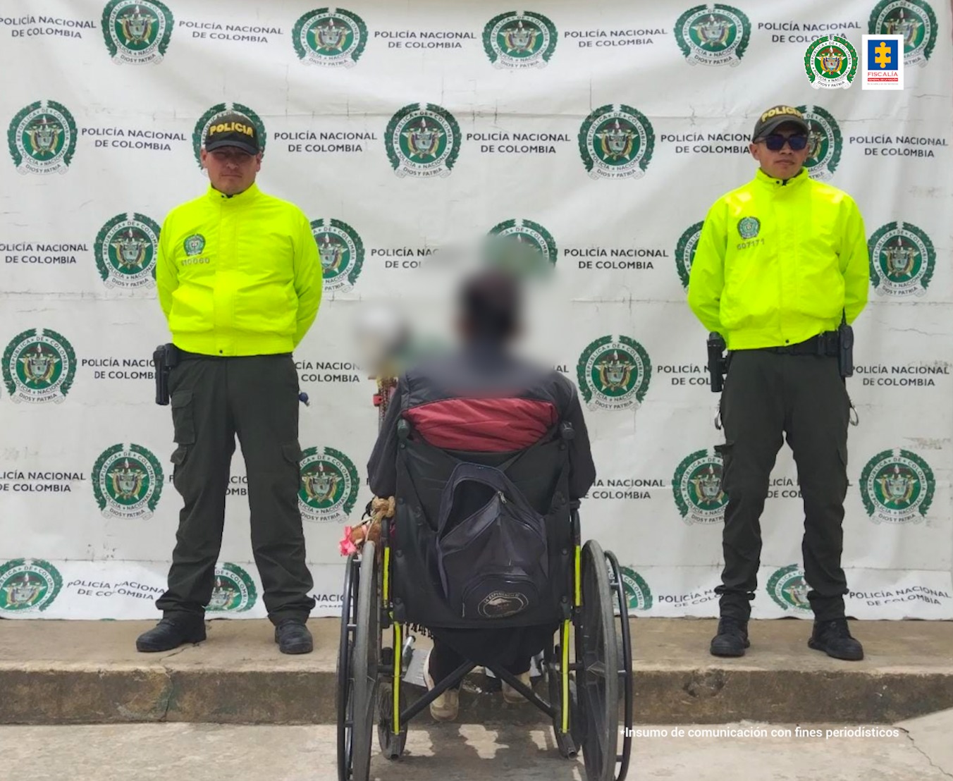 Un hombre aparece de espaldas, sentado en una silla de ruetas. A ambos costados tiene miembros de la Policía.