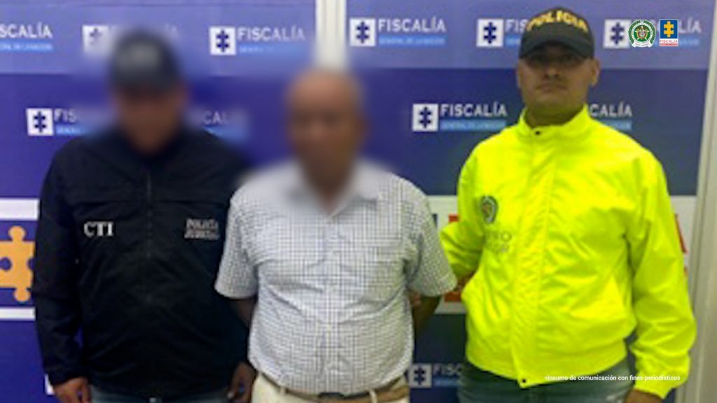 En la imagen aparece un señor de camisa de cuadros entre dos uniformados del CTI y la Policía Nacional.