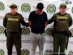 En la fotografía aparece el capturado junto con dos agentes de la Policía Nacional. En la parte superior está un banner de la Policía Nacional
