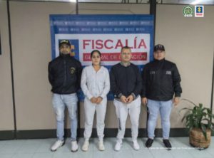 se observan un hombre y una mujer detenidos en el centro y a un costado un funcionario de CTI y al otro uno de Policía Nacional. Al fondo un pendón de Fiscalía General de la Nación