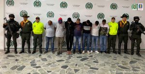 Se observan siete personas capturadas en fila. A cada costado de la fila tres servidores de la Policía Nacional. Atrás un pendón de Policía Nacional