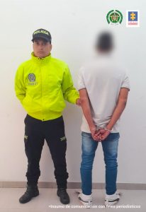 Se observa al capturado de espaldas y con sobre la cabeza un efecto de desenfocado, a un costado un funcionario de Policía Nacional.