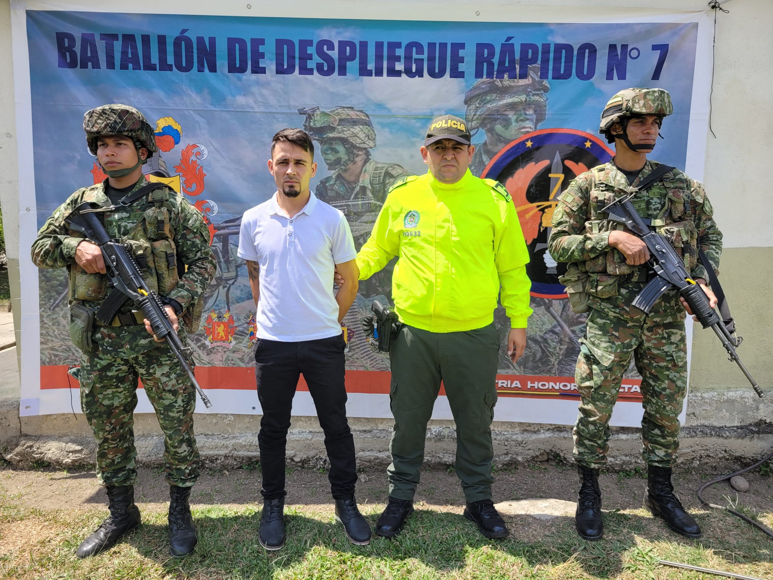 Se visualiza al capturado junto a uniformados del Ejército y la Policía Nacional. Detrás de ellos el banner que identifica al Ejército Nacional.