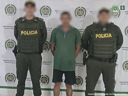 Se observa al capturado junto a dos uniformados de la Policía Nacional. Detrás el banner de la Policía Nacional.