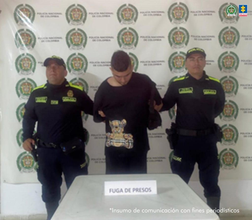 En la fotografía se aprecia de pie, con los brazos atrás y la cabeza agachada a Aimer Andrey Álvarez Bustos, alias El Gordo Andrey. Viste camiseta y pantalón de color negro. A sus extremos hay uniformados de la Policía Nacional. Delante de ellos hay una superficie blanca y sobre ella un letrero que dice: ‘Fuga de Presos’. Detrás de ellos hay un pendón institucional de la Policía.