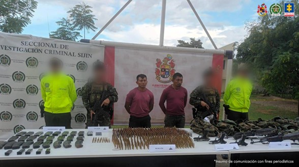 Se visualiza a los dos capturados junto a dos uniformados del Ejército y Policía Nacional. Frente a ellos una mesa con los elementos incautados como armas, munición, grandas y material de intendencia