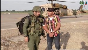 En la imagen se ve una persona detenida junto a un uniformado de la Policía y frente a un helicóptero.