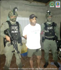 En la imagen se ve una persona detenida, con una camiseta blanca entre dos uniformados de la Policía.