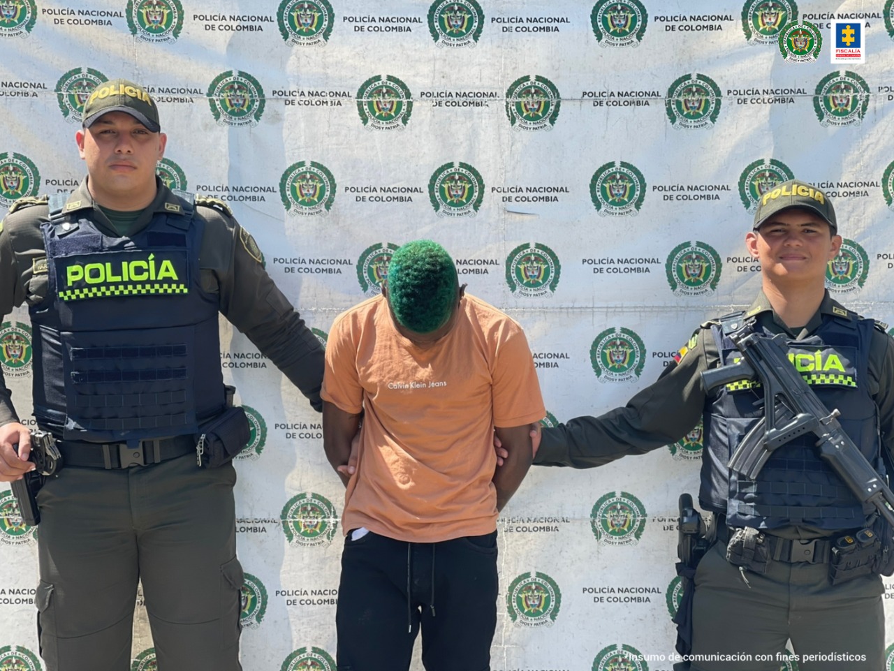 Se ve el capturado con la cabeza baja. A sus dos costados, dos miembros de la Policía.