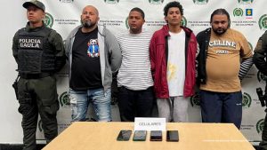 En la imagen están los 4 hombres con un servidor de la Policía Nacional a los lados y al frente una mesa con 4 celulares incautados 