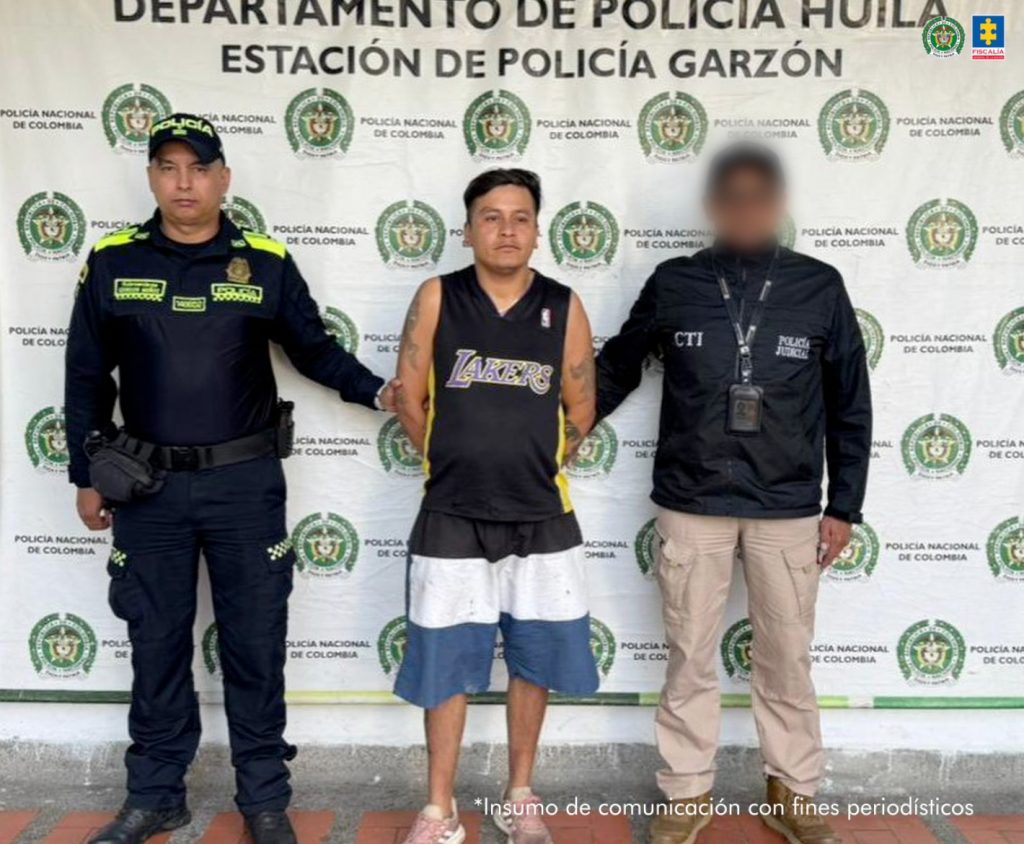 En la foto aparece el capturado custodiado por un servidor del Cuerpo Técnico de Investigación CTI y un uniformado de la Policía Nacional. En la foto también aparece de fondo un backing de la Policía Nacional.