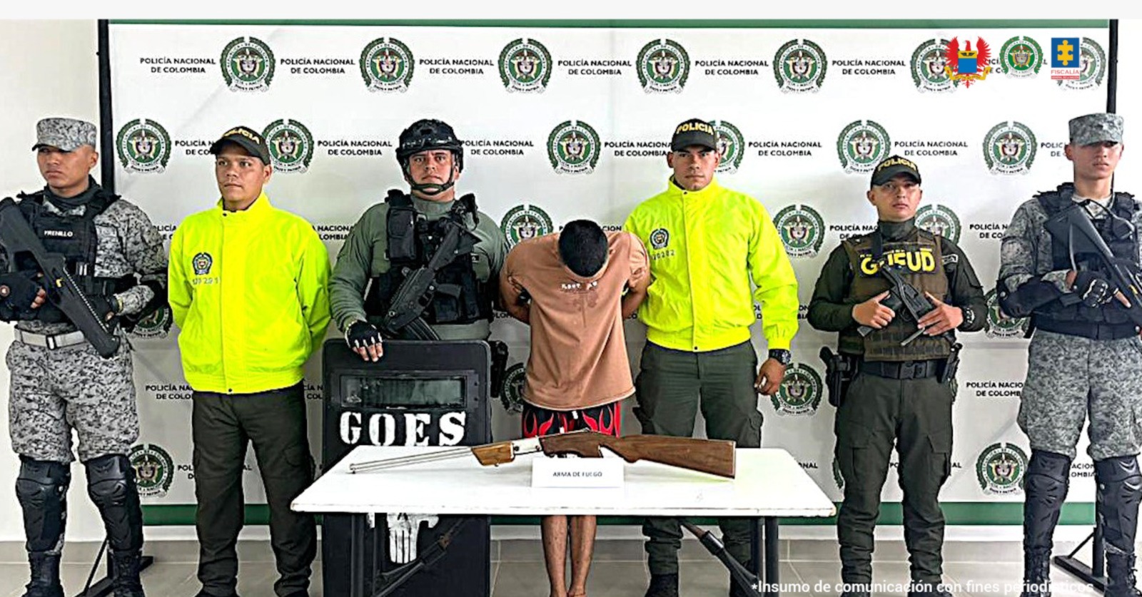 El apturado aparece con su rostro agachado con sus manos esposadas a la espalda y está custodiado por uniformados de la policía y la Fuerza Aérea Colombiana.
