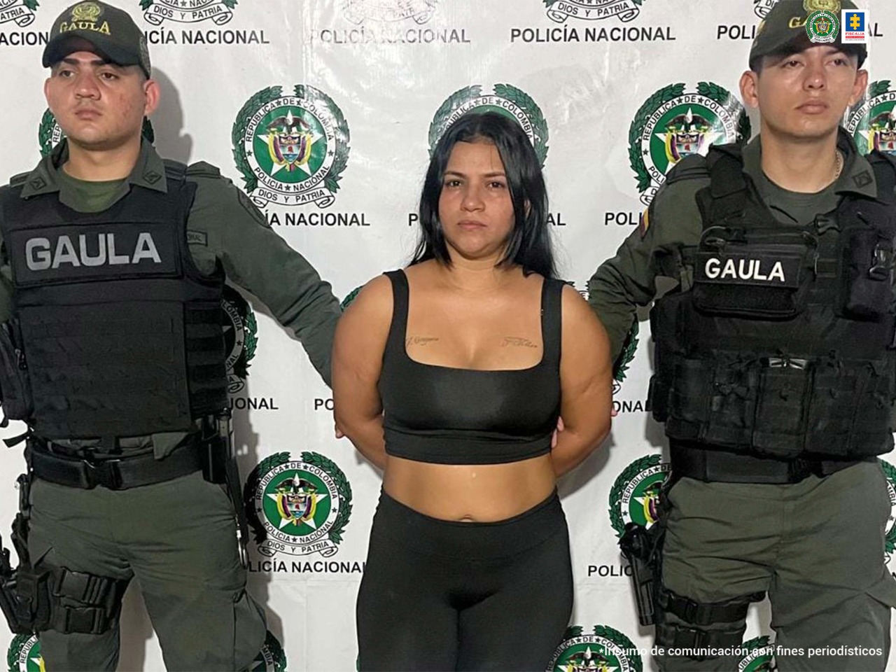 En la imagen se puede apreciar a la procesada en compañía de dos uniformados del Gaula de la Policía Nacional. De fondo se ve un backing con el logotipo de la Policía Nacional.