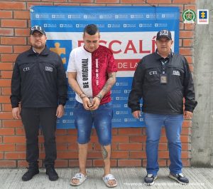 El capturado se encuentra de frente sobre un paredón de la Fiscalía en custodia de dos servidores del Cuerpo Técnico de Investigación CTI.