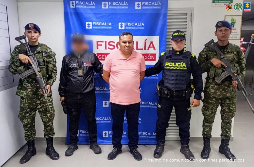 En la fotografía aparece el capturado junto a un servidor del CTI, un uniformado de la Policía y dos soldados del Ejército. En la parte superior está un banner de la Fiscalía General.