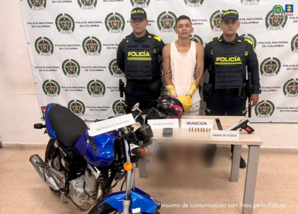 Se visualiza al capturado junto a dos uniformados de la Policía Nacional. Frente a ellos una mesa con los elementos incautados. Detrás de ellos el banner que identifica a la Policía Nacional.