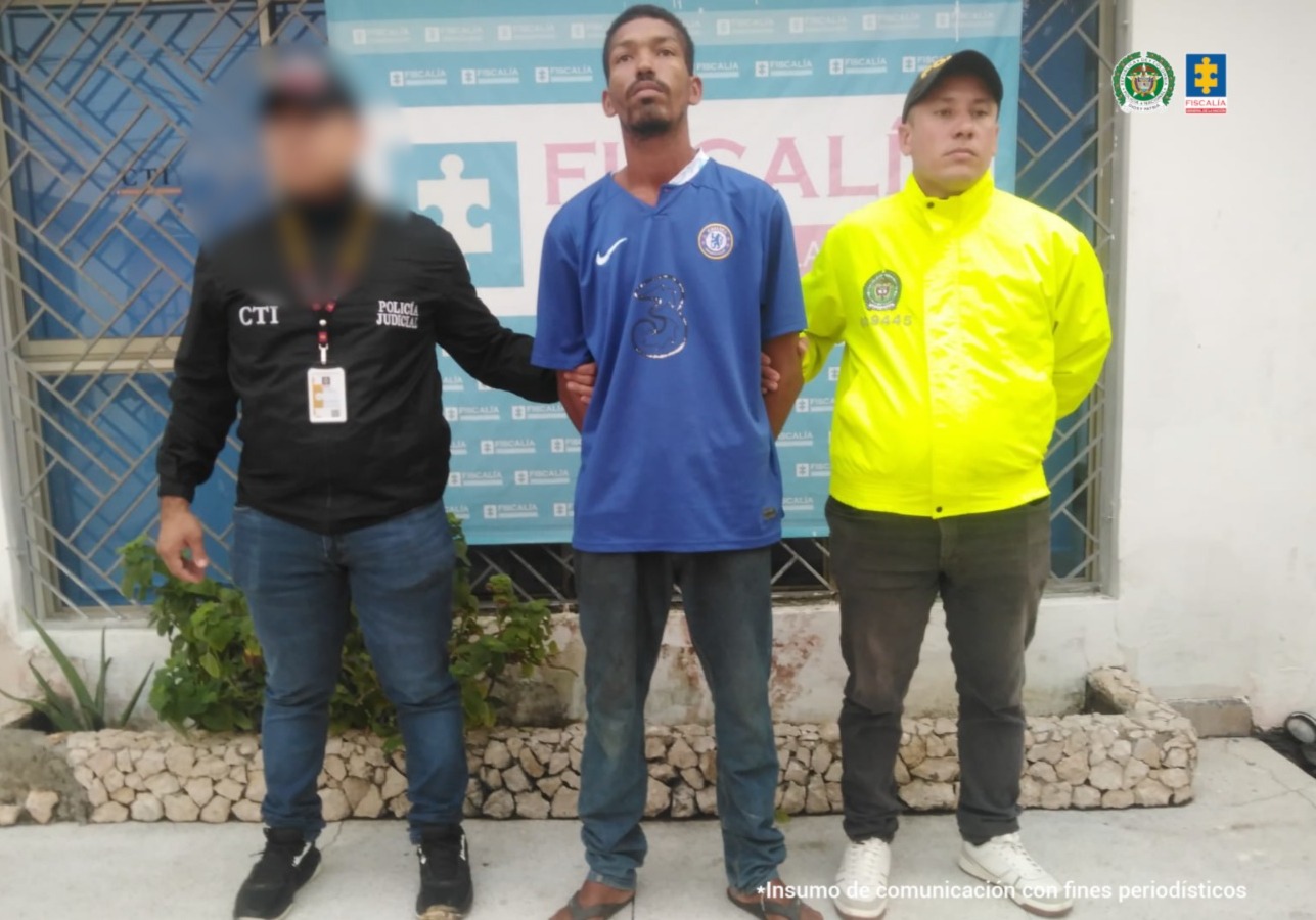 En la imagen aparece una persona de suéter azul entre un uniformado del CTI y de la Policía Nacional.