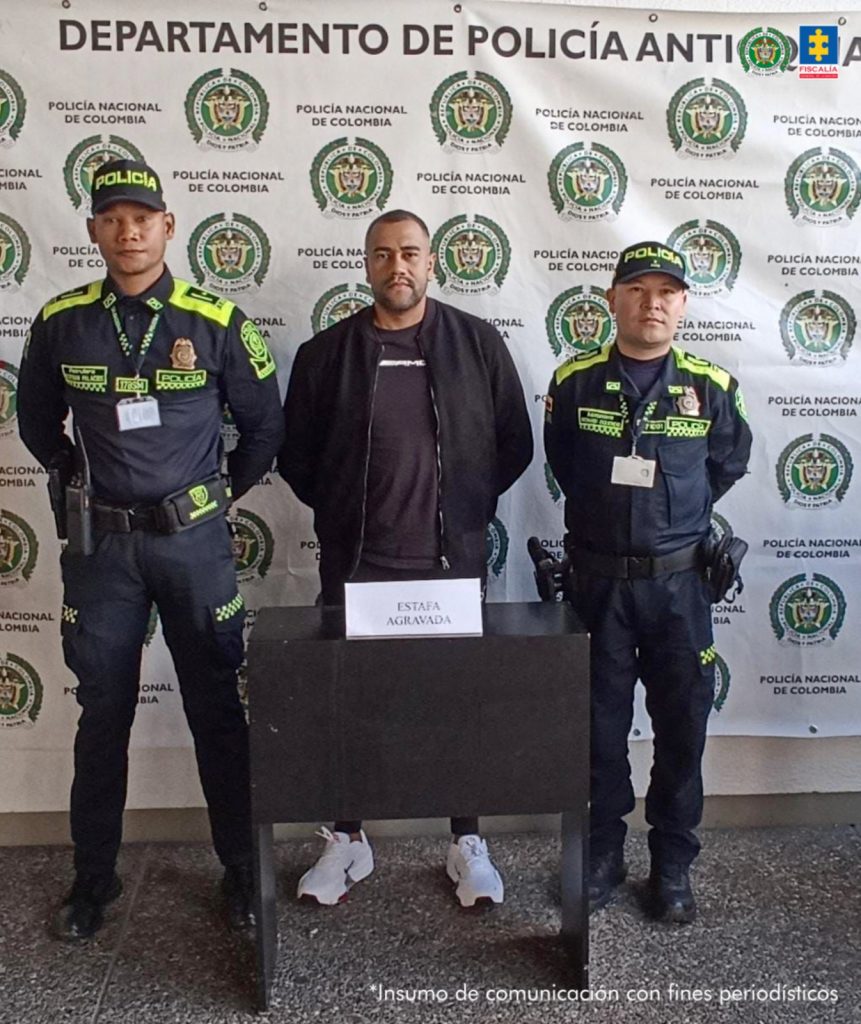 En la fotografía está el procesado en medio de 2 policías y atrás un pendón de la Policía Antioquia