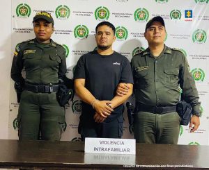 En la fotografía se aprecia de pie y con los brazos atrás a Andrés Mauricio Pineda Betancourt. Viste camiseta de manga corta de color negro y pantalón negro con bolsillos a los lados. A sus extremos hay uniformados de la Policía Nacional. Detrás de ellos hay un pendón institucional de la Policía.