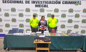 En la foto se aprecia a Angélica María Lucumí Carabalí, de pie y con los brazos atrás. Viste una blusa negra de manga larga con estampados de Micky y pantalón negro. A lado y lado de ella hay uniformados de la Policía Nacional. Delante de ellos hay una mesa larga con mantel verde y otra mesa cuadrada de madera. Sobre ellas hay múltiples elementos como computadores portátiles, relojes, dinero en efectivo, documentos de identidad, pasaportes, tarjetas de crédito, teléfonos celulares y prendas de vestir. Detrás de ellos hay un pendón institucional de la Policía Nacional.