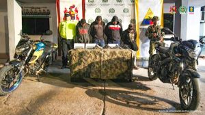 En la fotografía aparecen cuatro personas capturadas, acompañada de dos uniformados de la Policía y Ejército Nacional. En la parte posterior dos banners con logos de las entidades.