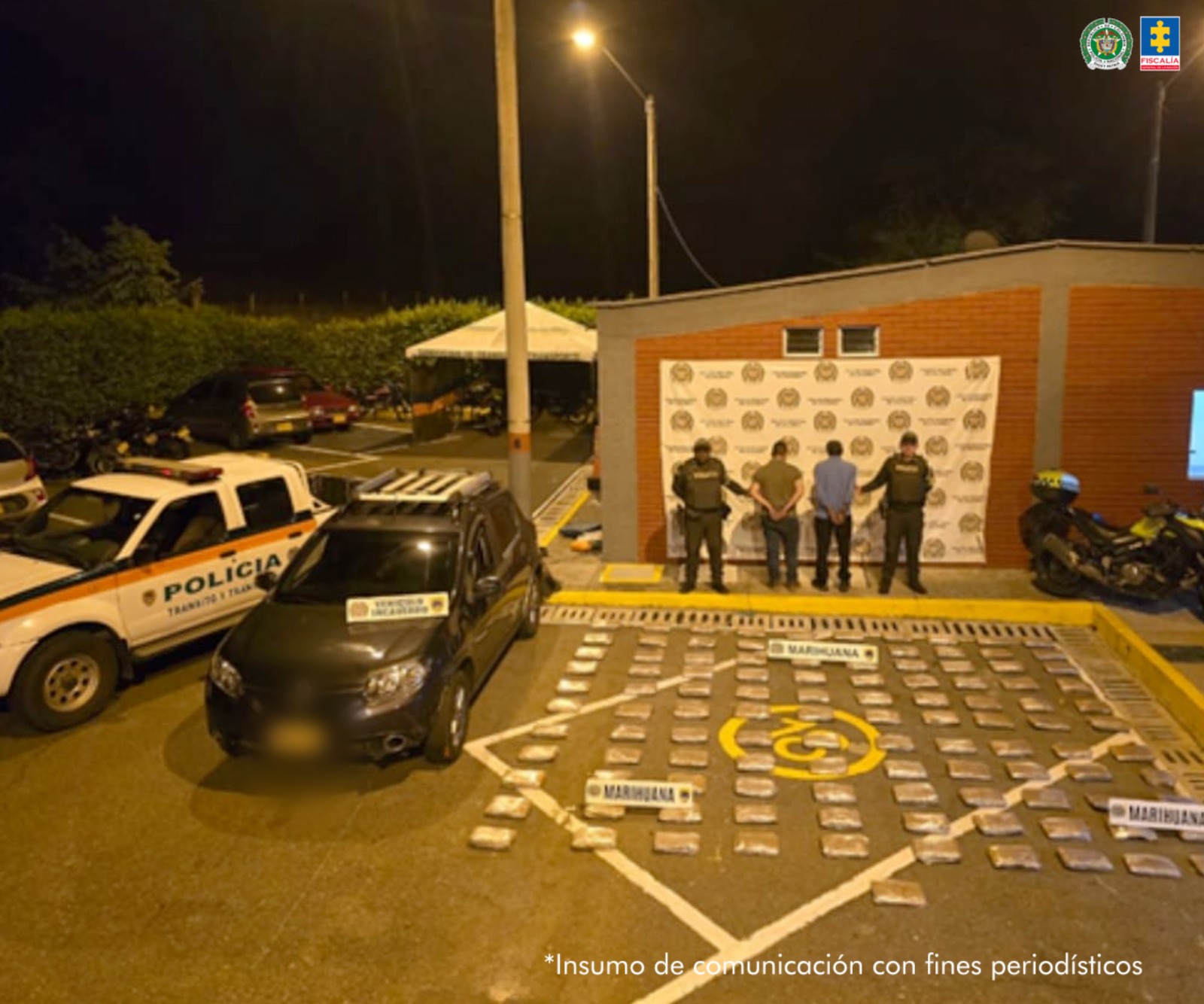 En la fotografía se tomó en exteriores y aprecian de pie, de espaldas a la cámara y esposados a Arley Estiben Muñoz Cano y Rafael Antonio Correa Ceballos. Uno viste camiseta verde, de manga corta y pantalón negro. El otro viste camisa azul de manga larga y pantalón negro. A sus extremos hay uniformados de la Policía Nacional. En el piso hay gran cantidad de paquetes envueltos en papel y tres letreros que dicen: ‘Marihuana’. Al lado derecho de los paquetes hay un vehículo. En la parte posterior hay un pendón institucional de la Policía.