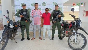 En la fotografía aparecen dos hombres capturados, acompañados de uniformados del Gaula Militar y de la Policía Nacional. En la parte posterior un banner con logos de la entidad.