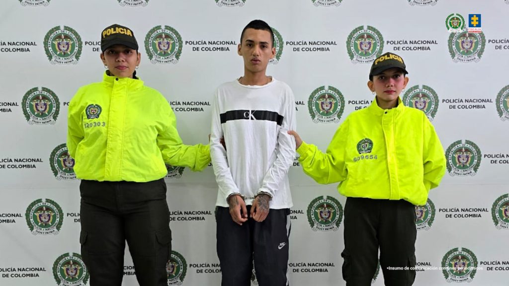En las imágenes aparecen los capturados esposados y custodiados por uniformados de la Policía Nacional, de fondo aparecen pendones institucionales de la fuerza pública.