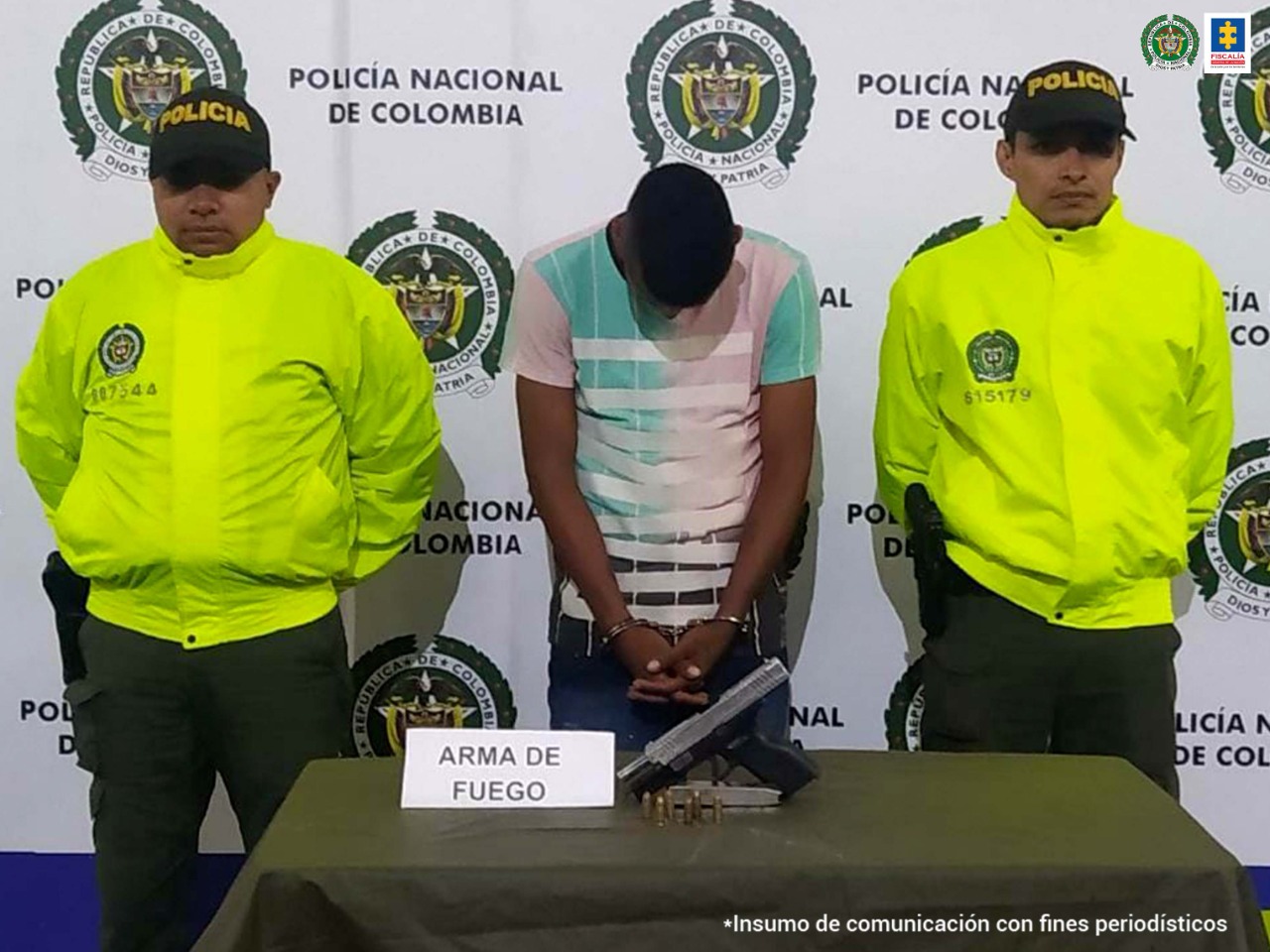 En la fotografía aparece el capturado junto a dos agentes de la Policía. En la parte posterior se ve una mesa con una pistola 9 milímetros