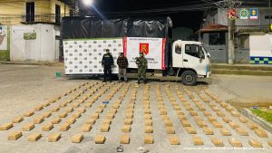 El capturado se encuentra en custodia por un uniformado del Ejército y Policía Nacional. Detrás se observa el camión donde al parecer, iba el estupefaciente camuflado. También se observa en el piso todos los paquetes donde iba oculto el alucinógeno. Detrás hay un backing de la Policía y Ejército Nacional.