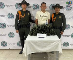 En la fotografía aparece el capturado junto a dos agentes de Carabineros de la Policía Nacional. En la parte posterior está una mesa con 15 uniformes pixelados y un teléfono celular