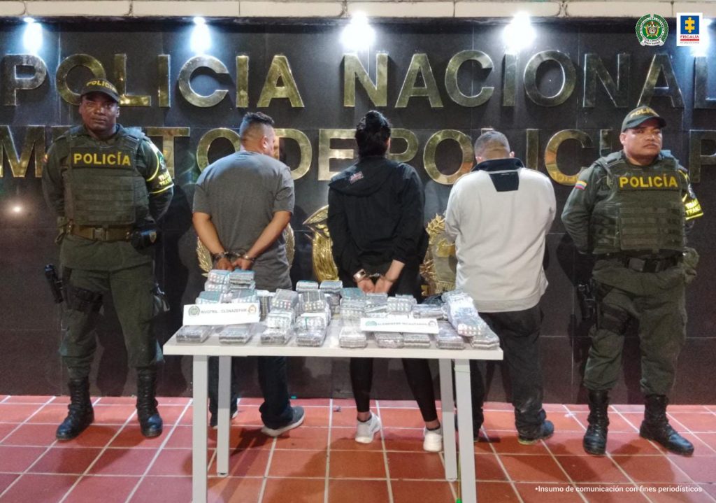 En la fotografía aparecen tres capturado, junto a personal de Policía Nacional. En la parte posterior de la imagen se ven banners de Policía Nacional y la Fiscalía General de la Nación.