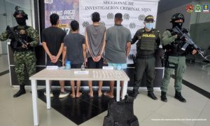 Se visualiza a los capturados junto a uniformados del Ejército y la Policía Nacional. Frente a ellos una mesa con los elementos hallados (granada y sustancias estupefacientes), Detrás se ubica el banner que identifica a la Policía Nacional.