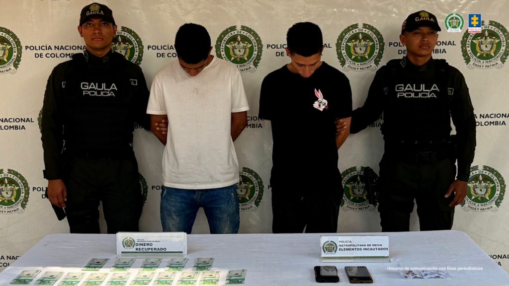 En la foto aparecen los dos capturados de frente y custodiados por dos uniformados de la Policía Nacional. En la foto también aparece un backing de la Policía Nacional y los elementos que les incautaron durante el procedimiento de captura.