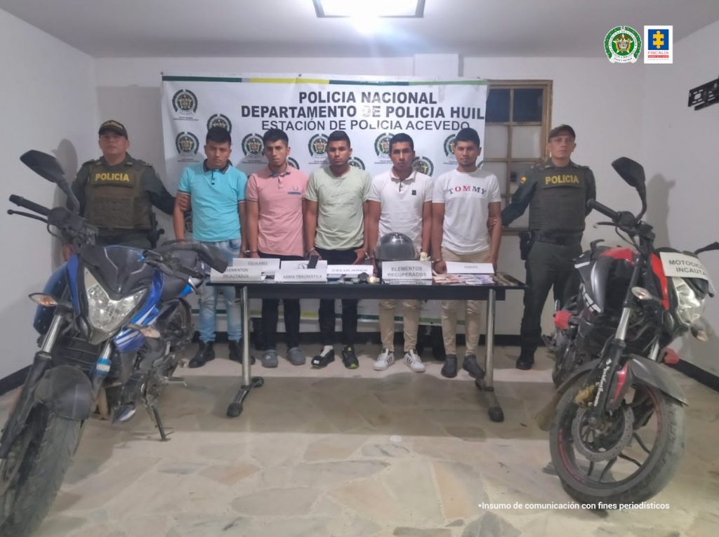 En la fotografía aparecen cinco capturados, junto a personal de Policía Nacional. En la parte posterior de la imagen se ven banners de Policía Nacional y la Fiscalía General de la Nación.
